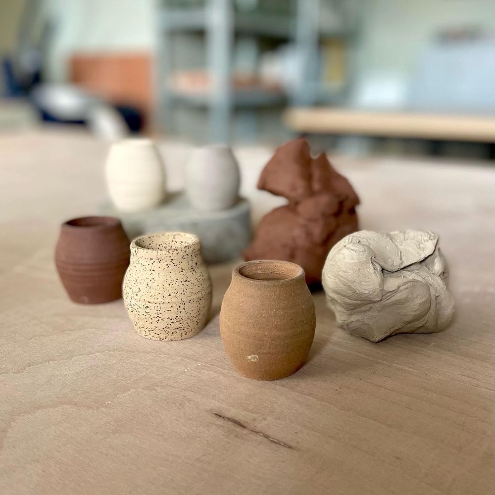 Collection of ceramic pots and sculptures on a wooden surface with a blurred indoor background.